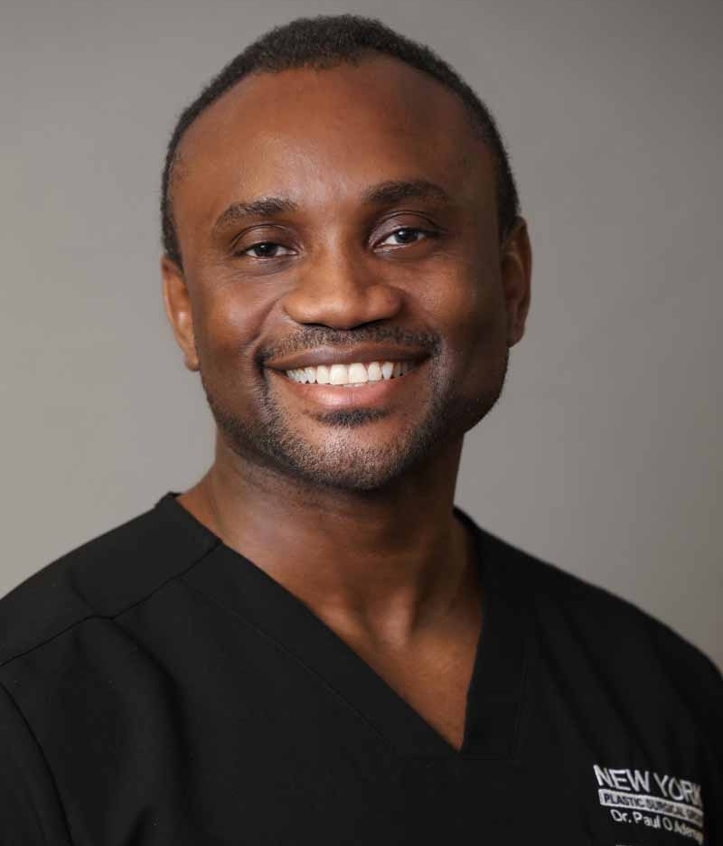 Dr. Paul Adenuga in medical scrubs